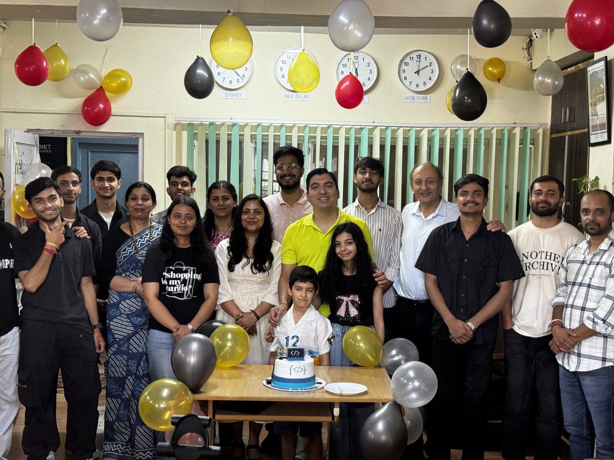 The Netgen team and their families, two children among them, gathered around the anniversary cake in the Shimla office under balloons and world-time wall clocks