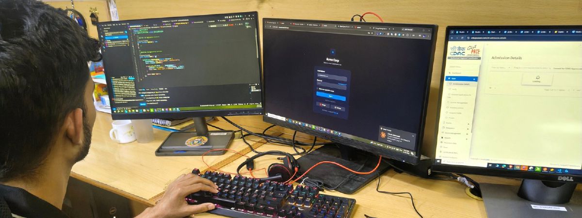 A Netgen developer at a three-monitor desk in the Shimla office, with code open on the left screen