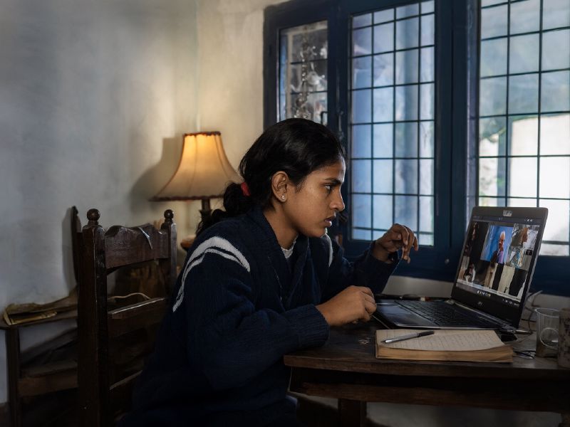 Photo (AI-generated, illustrative): a school student attends an online class on a laptop at home