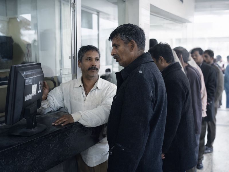 Photo (AI-generated, illustrative): a clerk at a district office counter shows a citizen the status of his application on screen