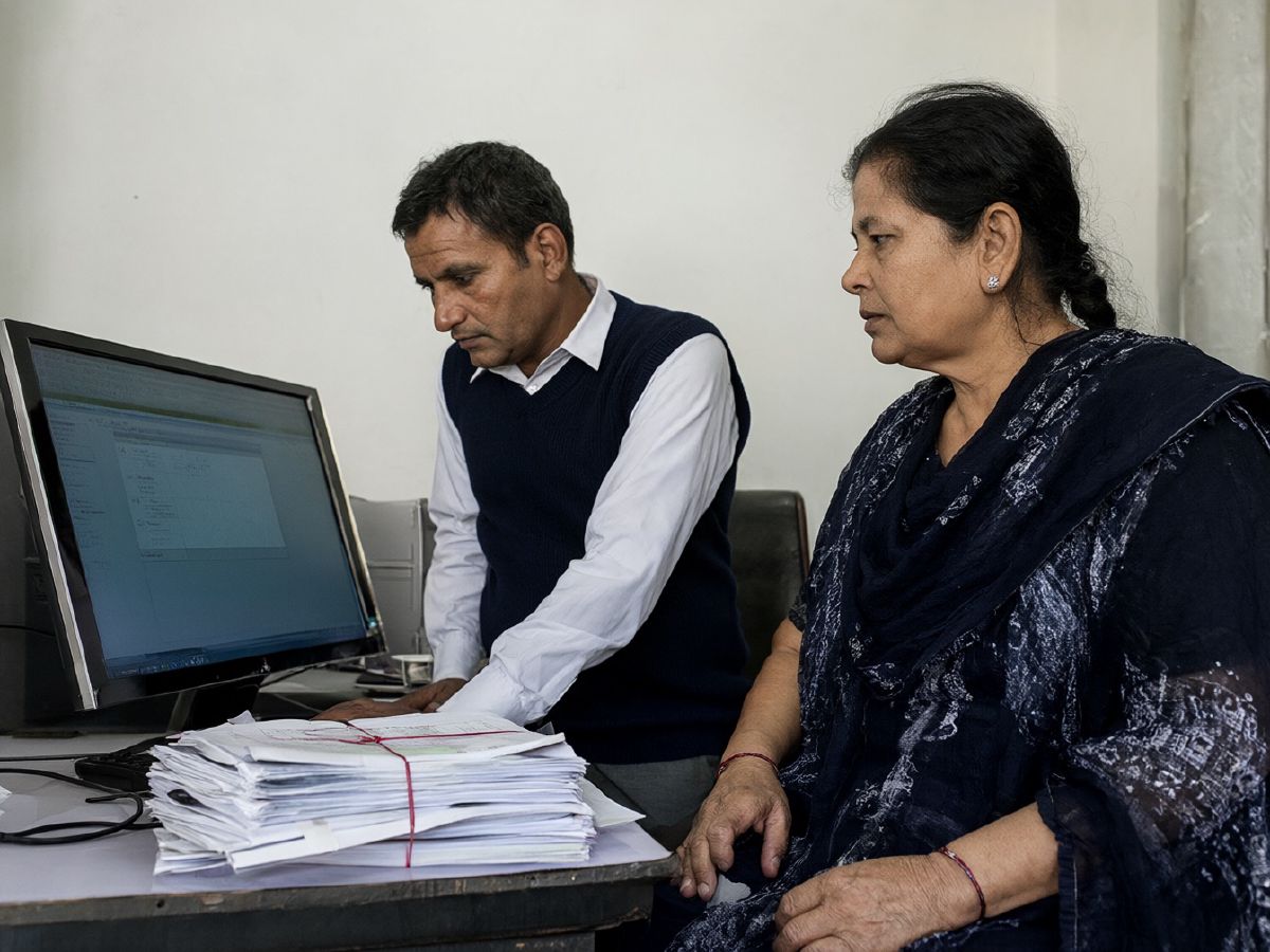 Photo (AI-generated, illustrative): two department officials review a digital file on screen beside stacks of paper files