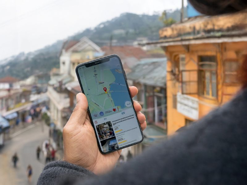 Photo (AI-generated, illustrative): a tourist on a hill station street checks a business listing on a map app